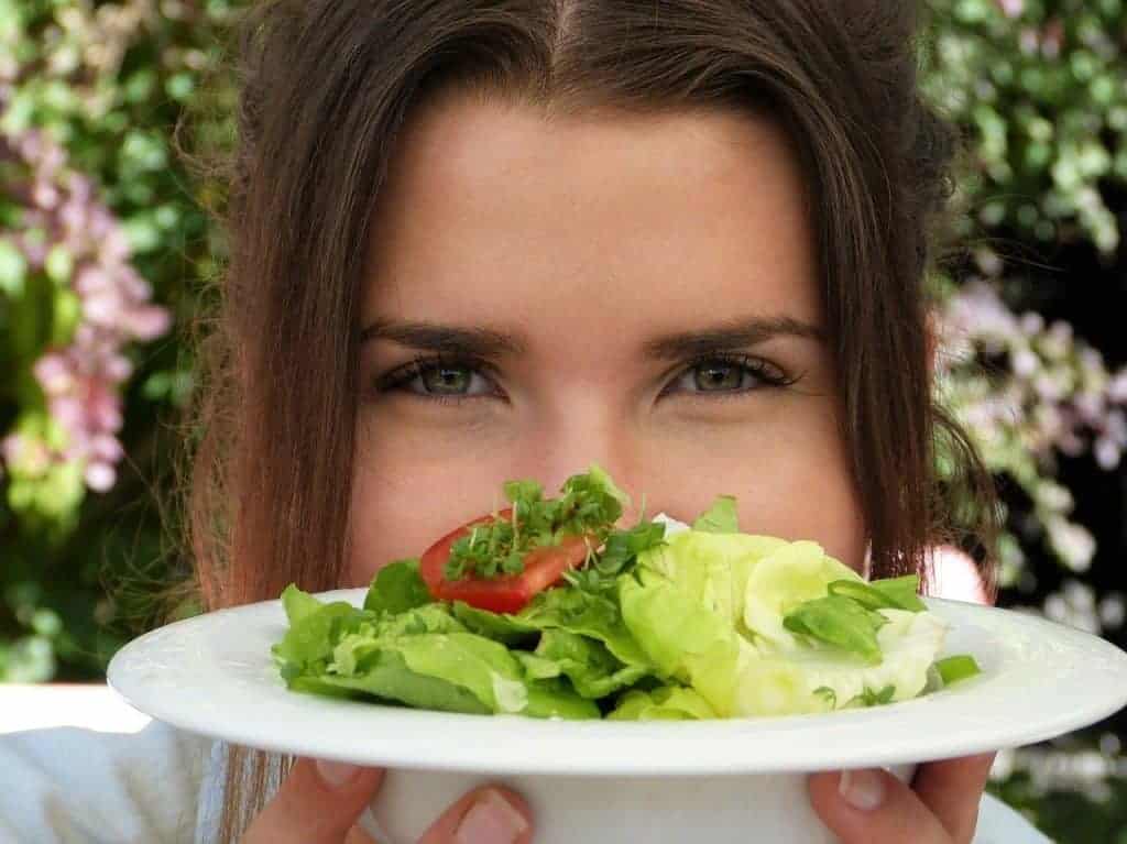 a mulher está a segurar um prato de salada